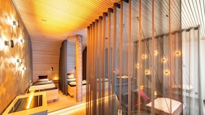 A modern hotel room with a unique ceiling design, a large bed, a sitting area, and a separate sleeping area. - Resort La Ginabelle (Zermatt)