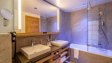 A modern bathroom with two sinks, a large mirror, a glass-enclosed shower, and a wooden vanity.