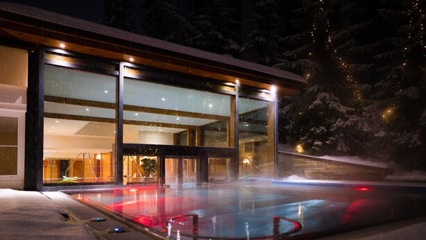 A modern building with large glass windows and a heated outdoor pool area. - Resort La Ginabelle (Zermatt)