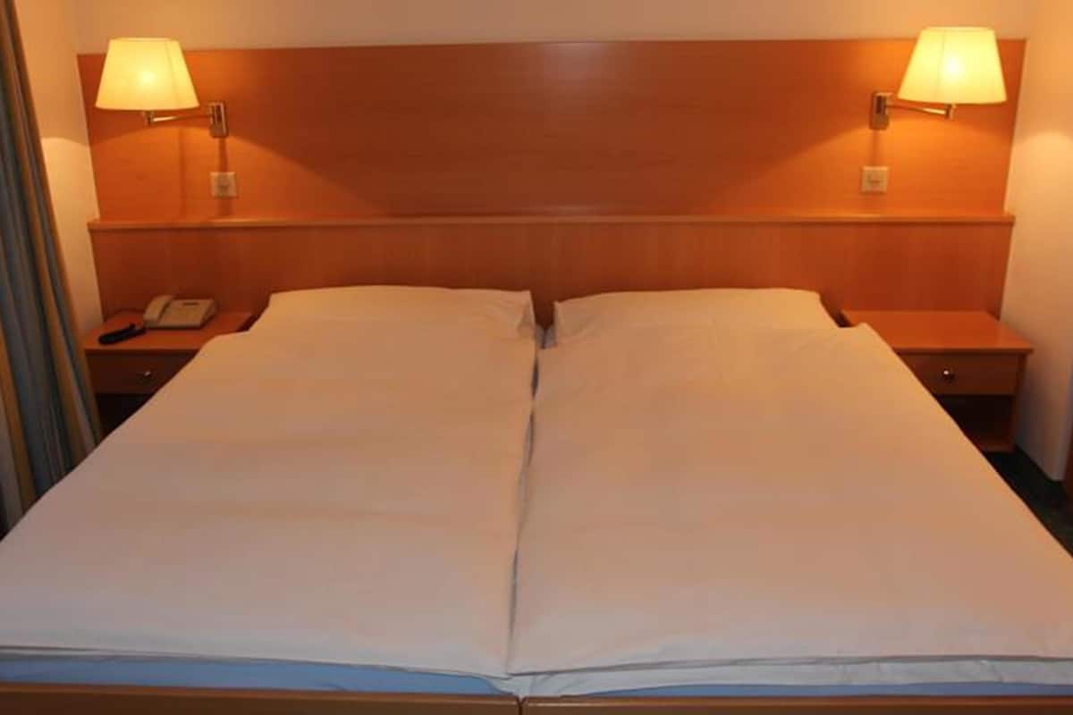 A double bed with two nightstands, each with a lamp and a phone.