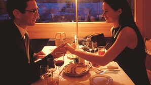 Una pareja cenando en una mesa con vistas a una cadena montañosa.