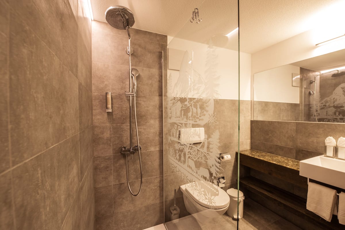 A modern bathroom with a glass shower enclosure, a toilet, and a sink with a vanity.