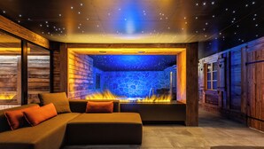 A cozy lounge area with a stone wall fireplace, comfortable seating, and a starry ceiling. - Hotel Daniela (Zermatt)