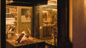 A room with a glass partition, a fire feature, and a view of the interior including a dining area and a wall-mounted picture. - Hotel Daniela (Zermatt)