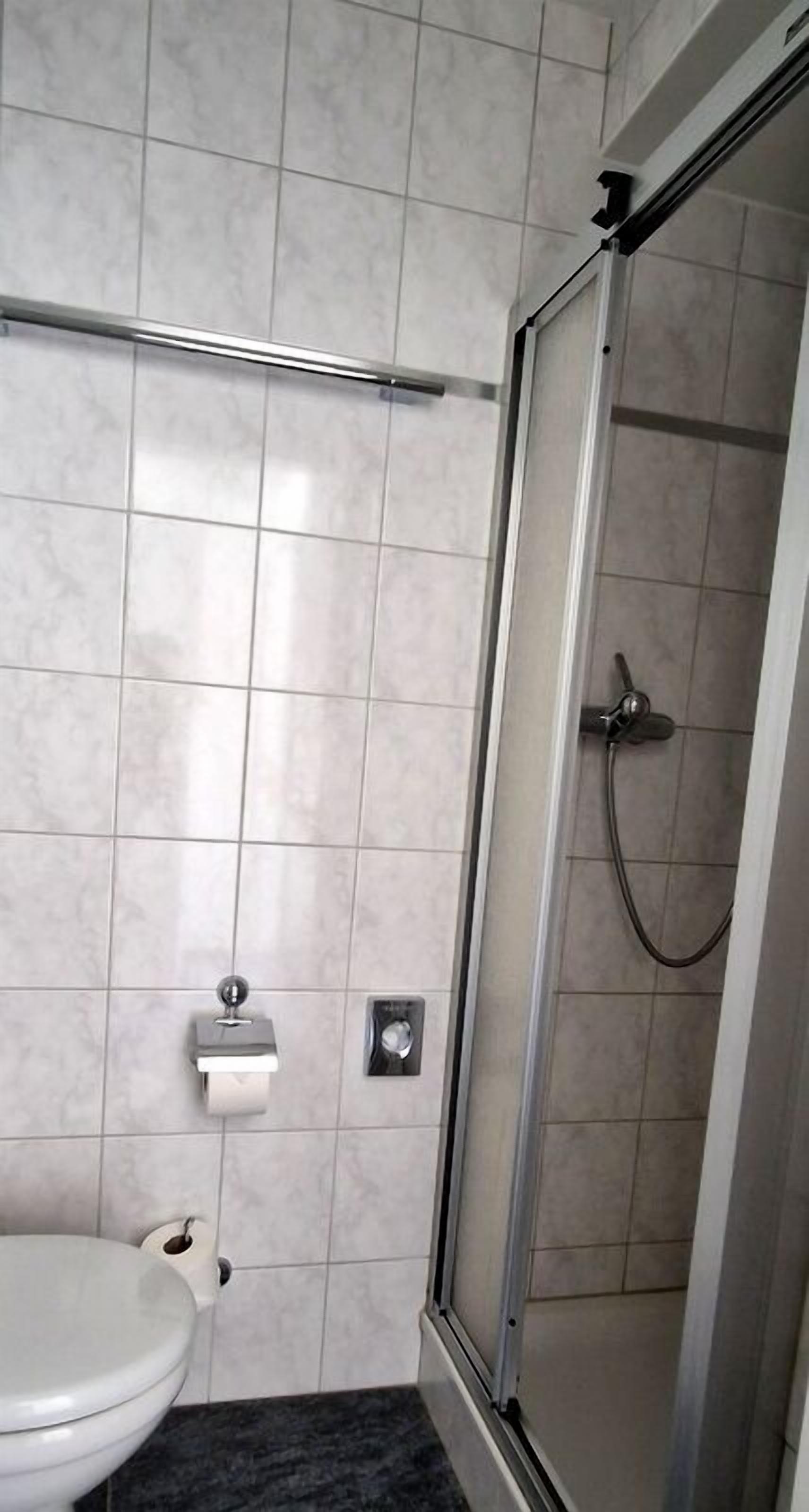 Un bagno con il water, una doccia con porta in vetro e un porta asciugamani.