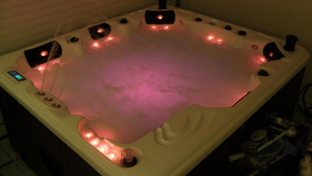 Ein Whirlpool mit zahlreichen Düsen, einer Bedienkonsole und LED-Beleuchtung.