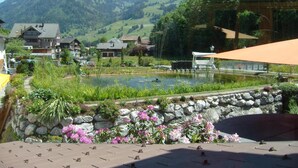 Seeblick mit Steinmauer, Blumen und einem Pavillon.