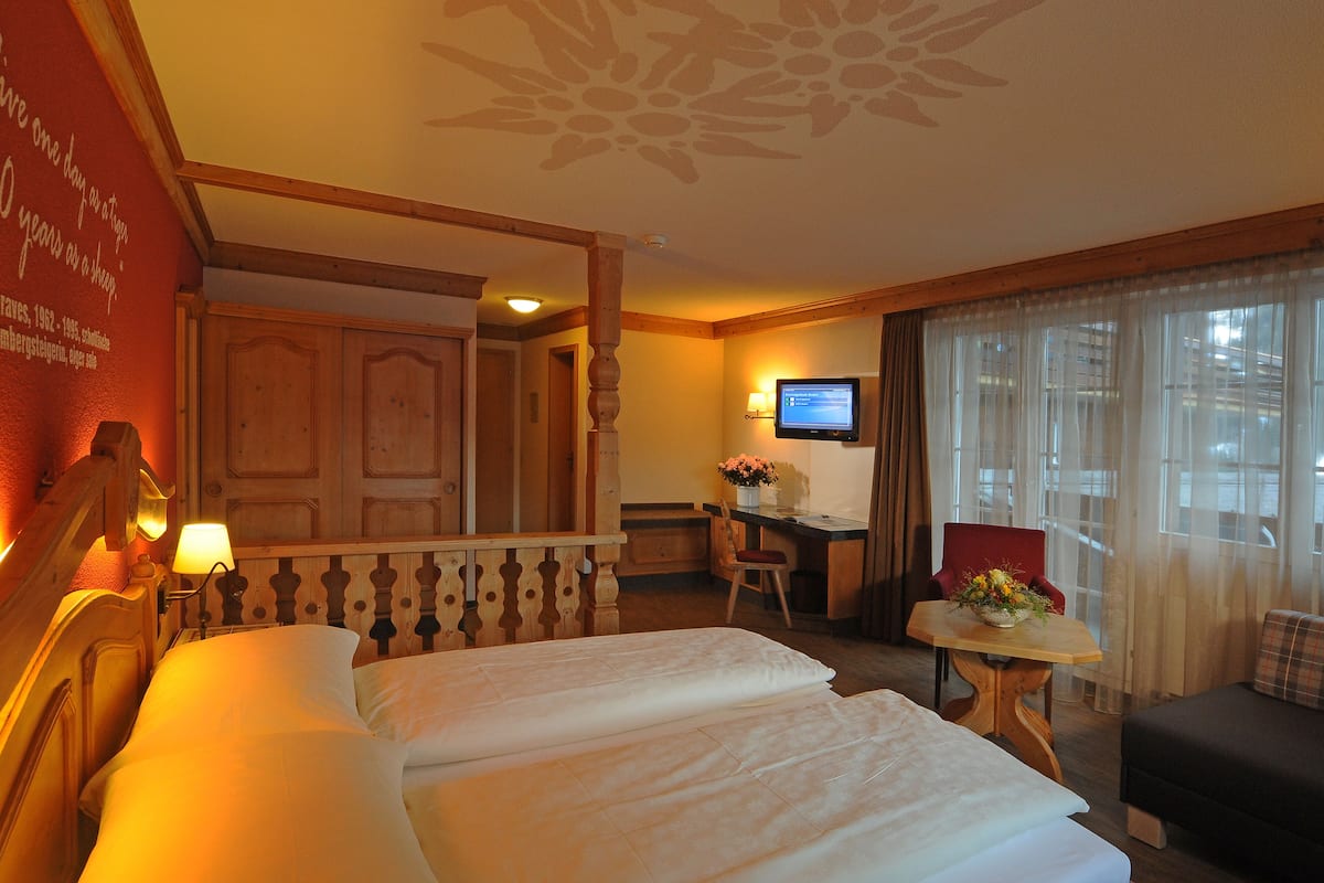 A hotel room with a bed, a desk, a chair, a television, and a window with curtains.