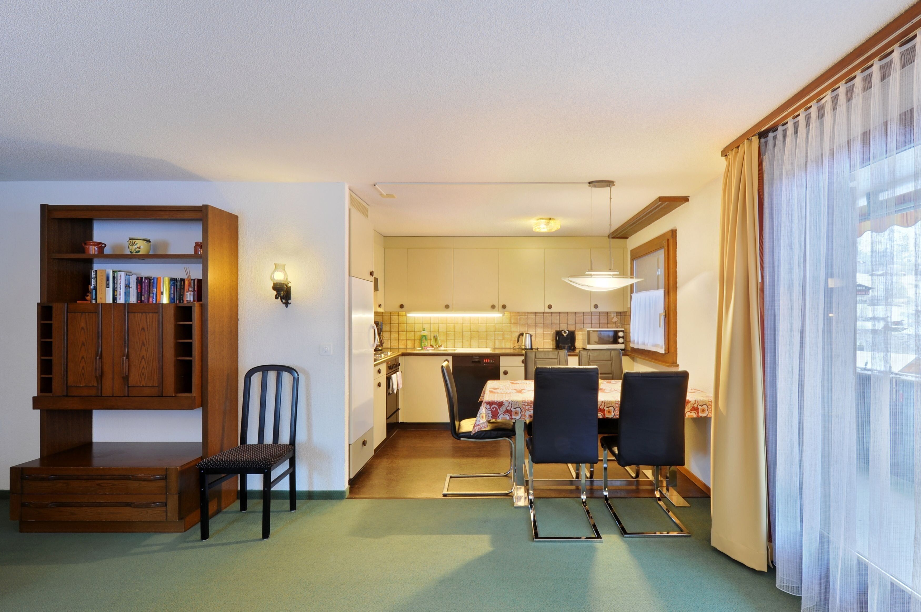 A compact living space with a kitchenette, dining area, and a bookshelf.