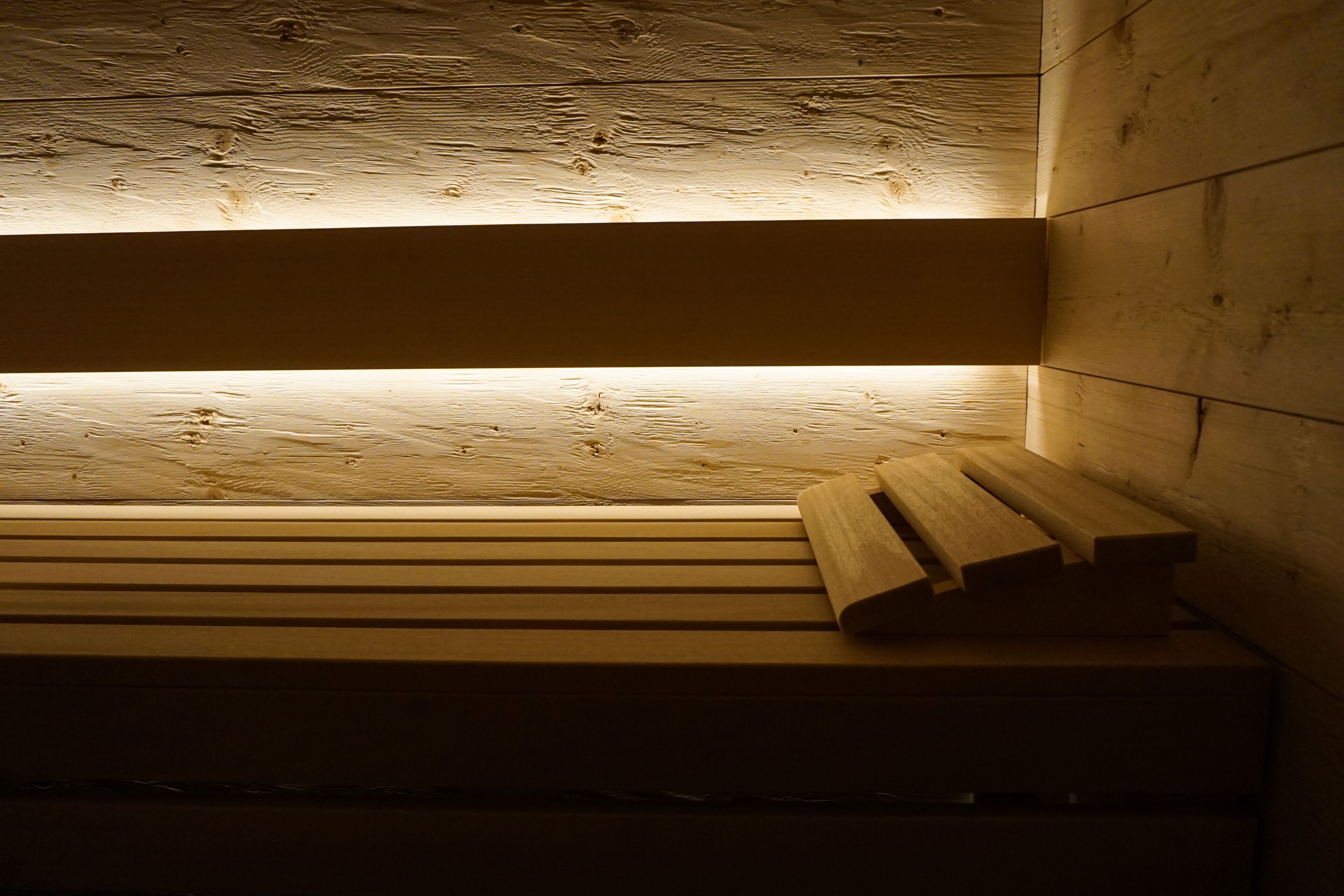 Un banc en bois à lattes, placé contre un mur dont la surface est texturée.
