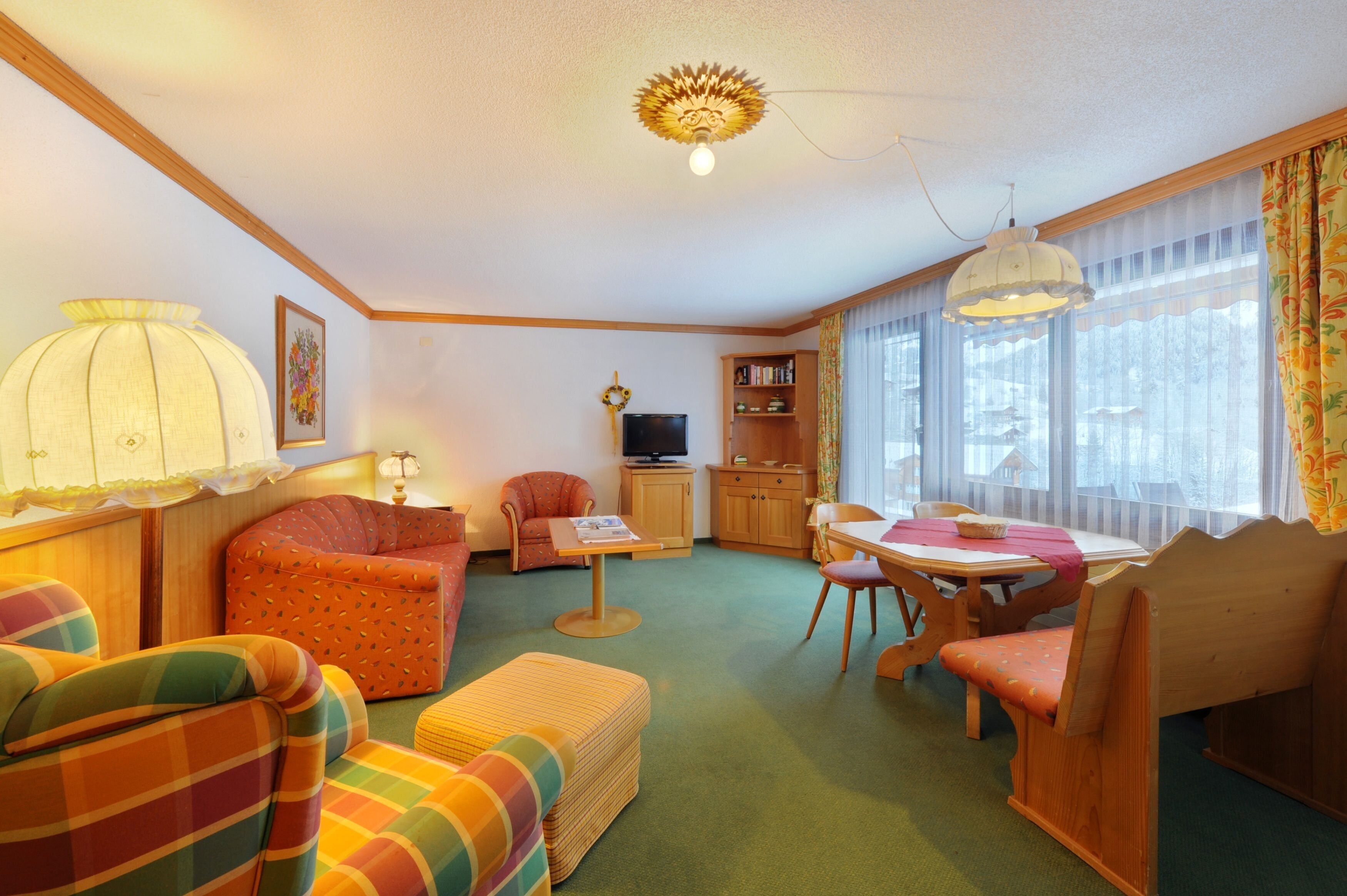 Una sala de estar acogedora con sofá, sillón, mesa de comedor y televisor.
