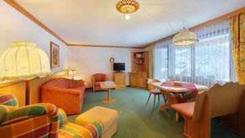Una sala de estar acogedora con sofá, sillón, mesa de comedor y televisor.