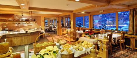 A buffet area with various food items and a view of a snowy landscape through large windows.