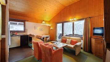 A cozy cabin interior with a dining area, sofa, and television.