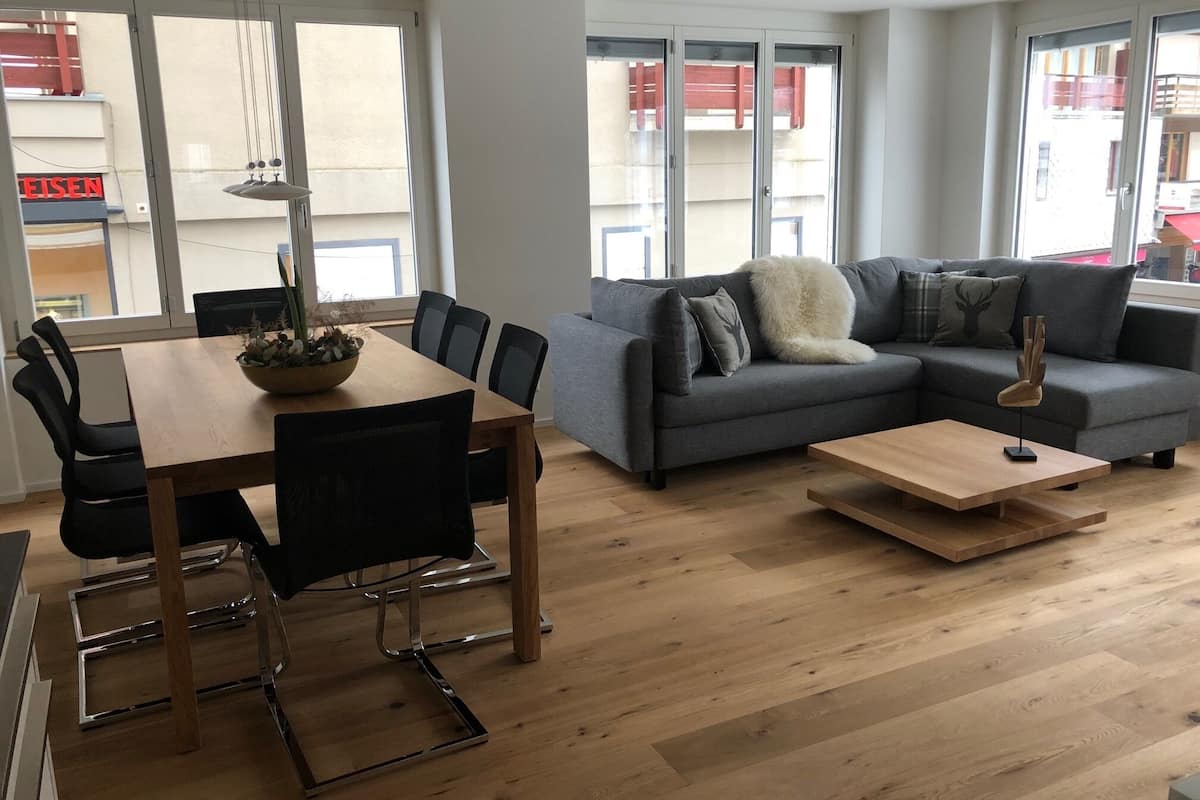 Un salon moderne avec un coin repas, comprenant un canapé gris, une table basse en bois et une table à manger avec des chaises.