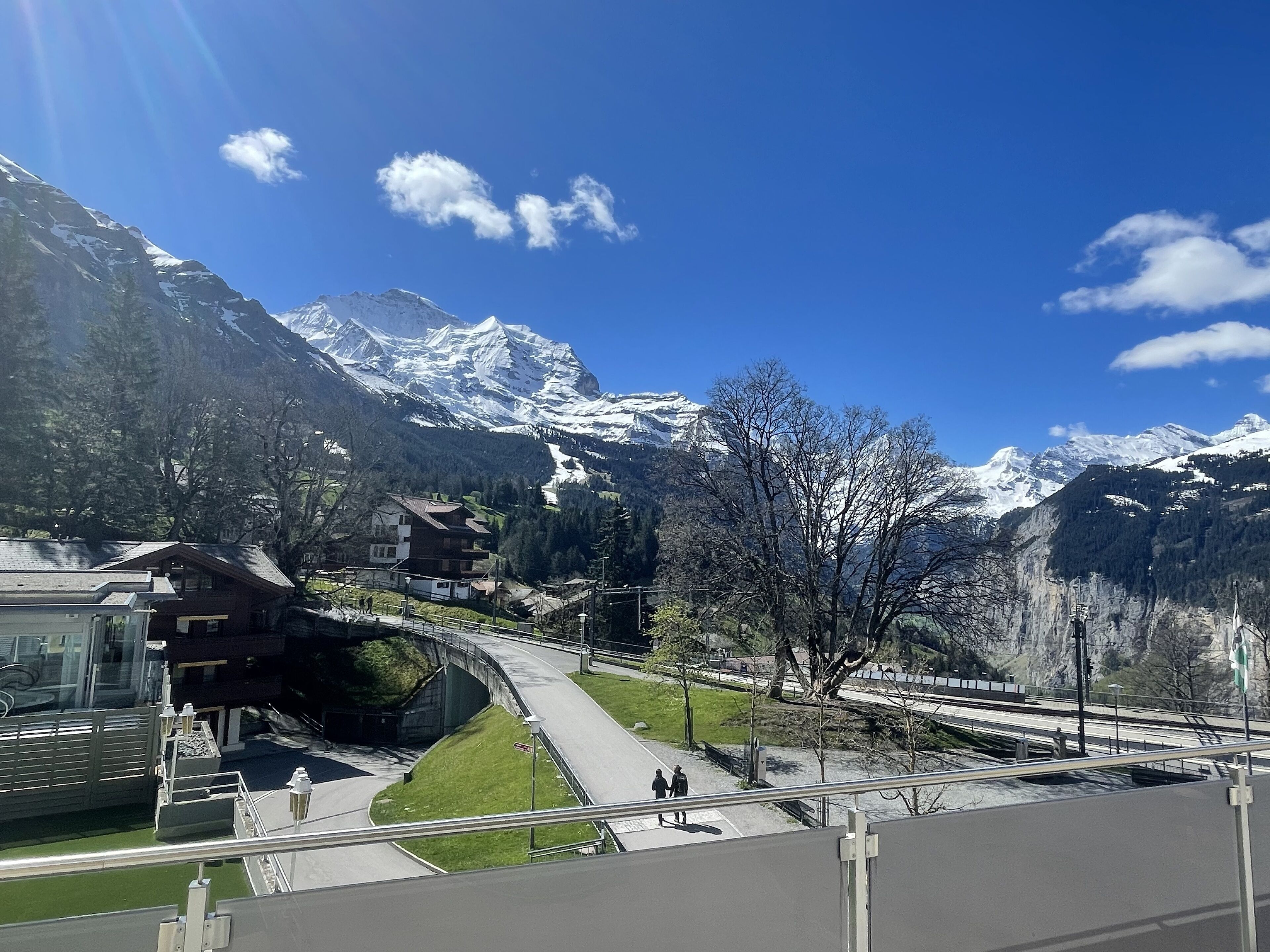 A mountain landscape with snow-capped peaks, a bridge, and a road.