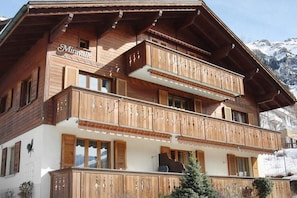 A wooden chalet with balconies, named "Miravalle," set against a mountainous backdrop.