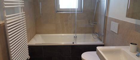 Un baño con bañera, inodoro y ventana.