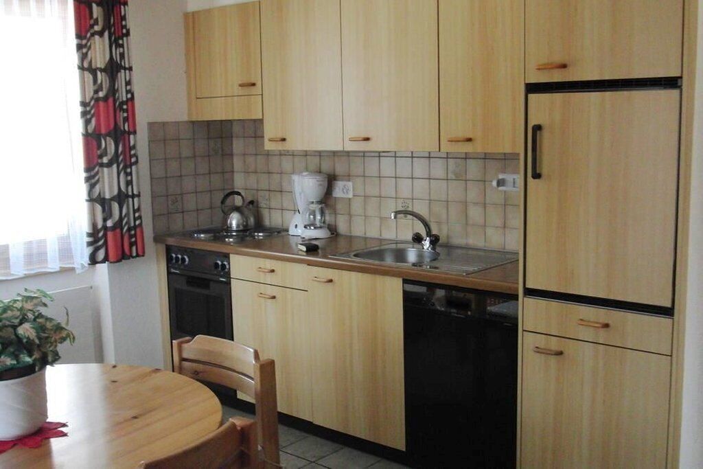 Una cocina con armarios de madera, un fregadero, un hervidor, una cafetera y un lavavajillas.
