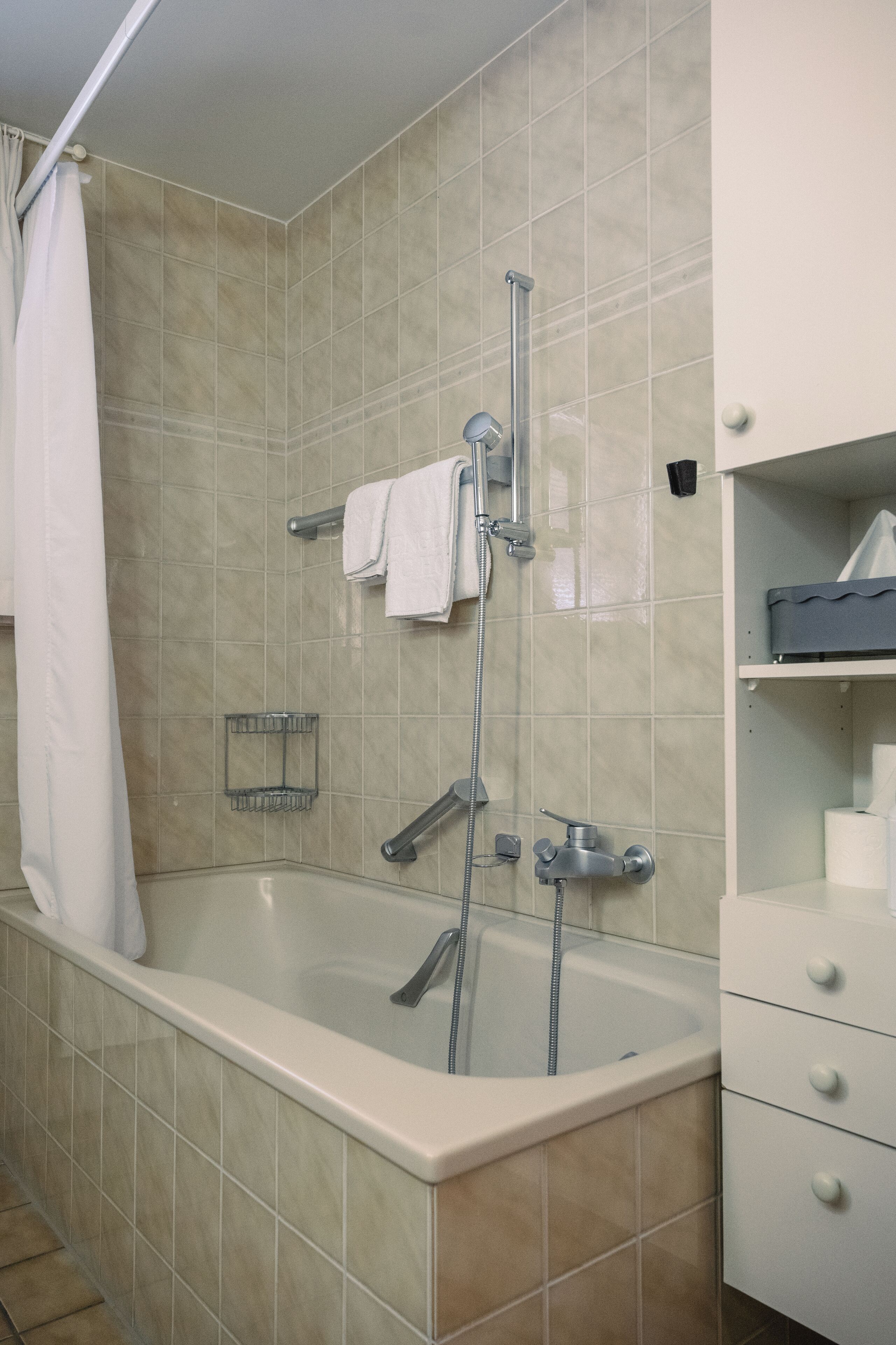 A bathroom with a bathtub, shower, and white tiled walls.