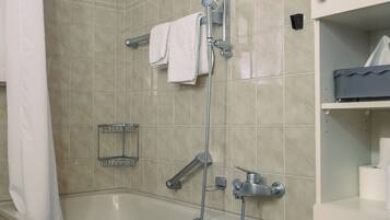A bathroom with a bathtub, shower, and white tiled walls.