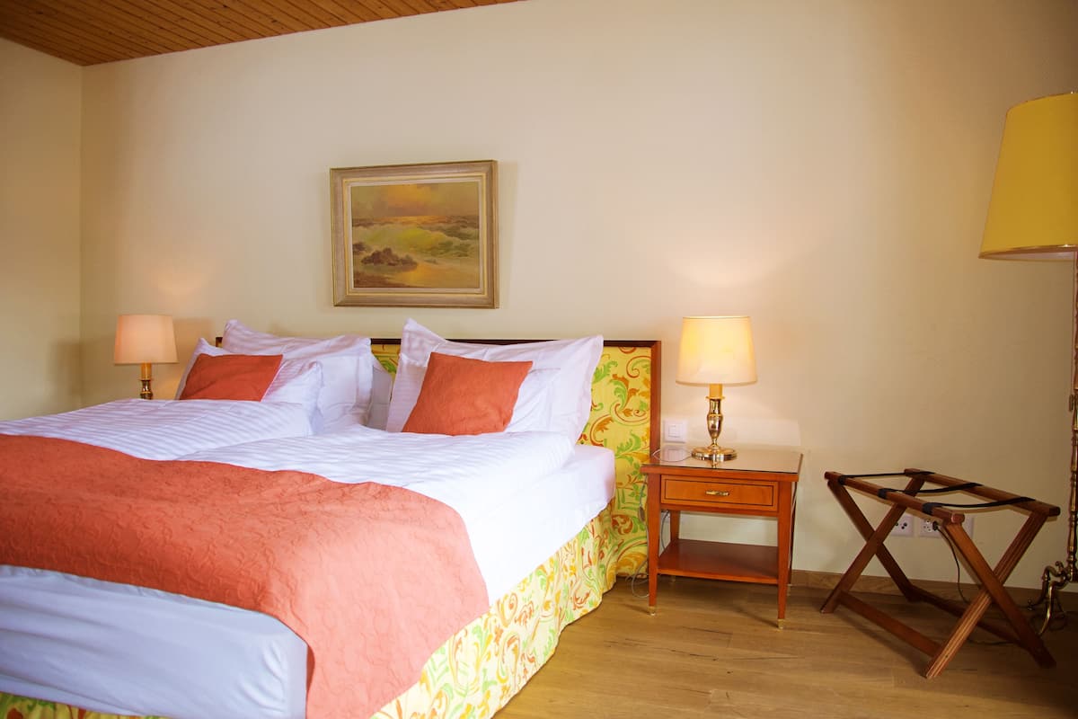 Une chambre d’hôtel avec un grand lit, deux tables de chevet, une lampe et un tableau au mur.