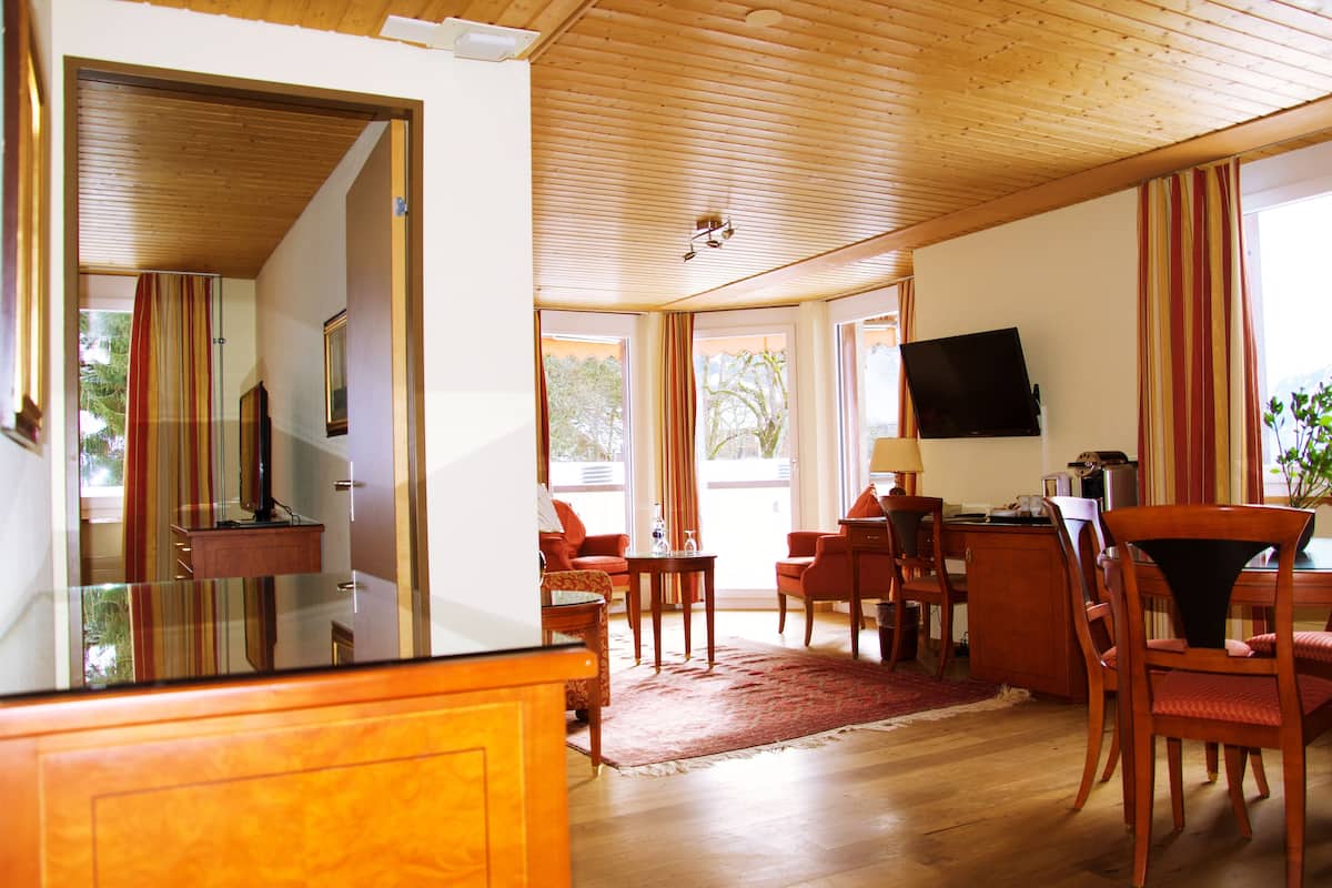 Un vaste salon doté d’un plancher en bois, d’un grand téléviseur fixé au mur et d’un coin repas avec des meubles en bois.