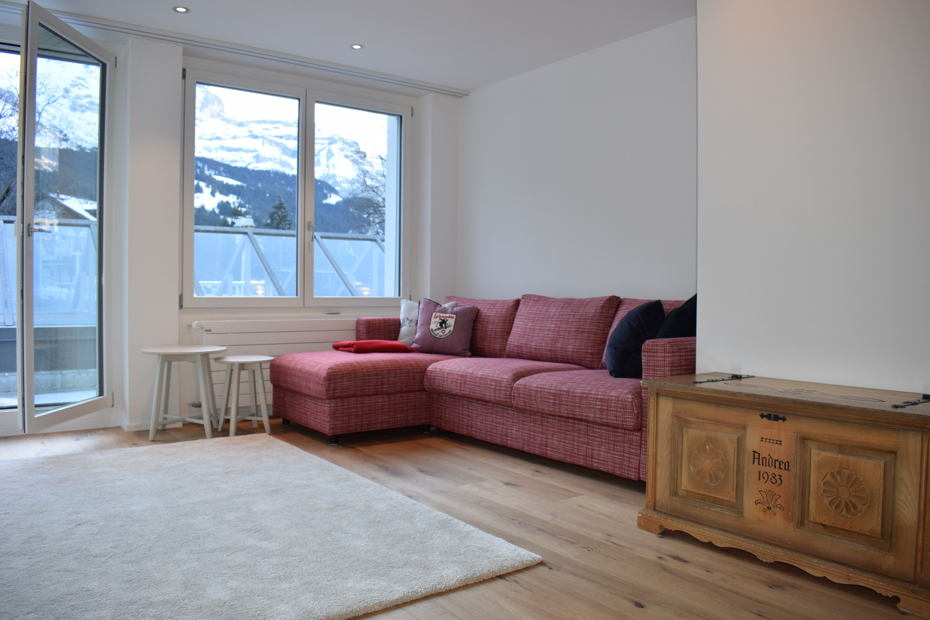 Un salon moderne avec un canapé rouge, une petite table blanche et un meuble en bois.