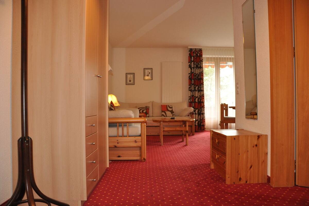 Une pièce comprenant une armoire en bois, un canapé, une petite table et un miroir.
