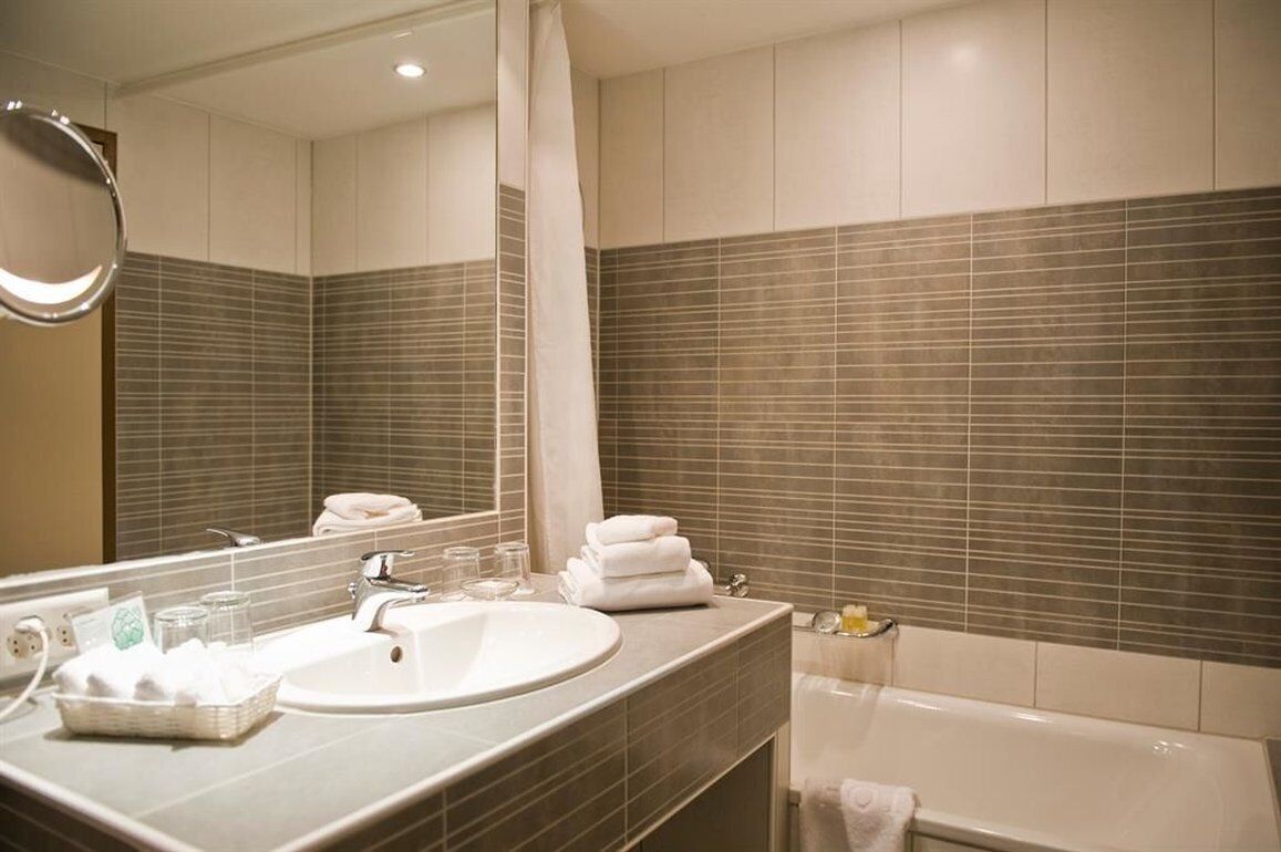 Un baño moderno con un espejo grande, un lavabo y una bañera.