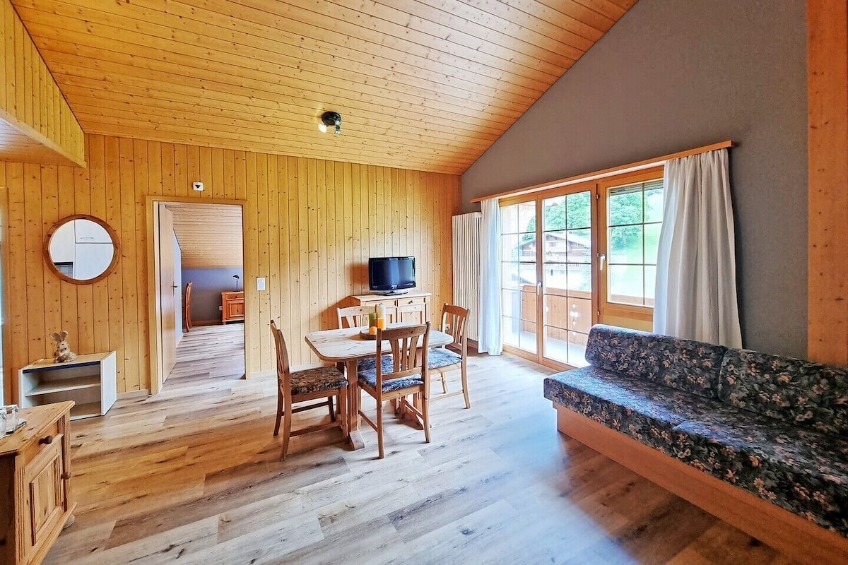 A wooden interior with a dining area, a sofa, and a television.