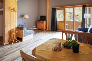 Un salón acogedor con un sofá, una mesa de comedor con una planta y un televisor al fondo.