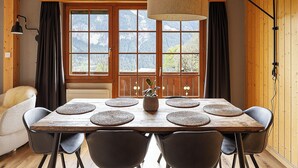 Una mesa de comedor de madera con individuales tejidos, seis sillas y una lámpara colgante.