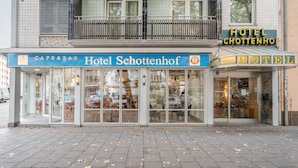 Hotel Schottenhof, un hotel amb una cafeteria i bar a la planta baixa, grans finestres i un balcó.