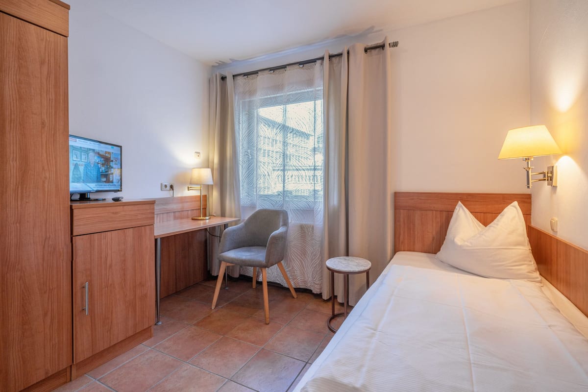 Une chambre d’hôtel équipée d’un lit, d’un bureau, d’une chaise, d’une télévision et d’une fenêtre avec des rideaux.