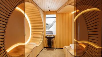 Ein moderner Wellnessraum mit Holzschubwänden, einem zentralen Waschbecken und Blick ins Freie.