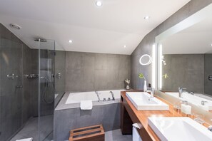 Ein modernes Badezimmer mit einer Glasdusche, einer großen Badewanne und zwei Waschbecken mit Spiegeln.