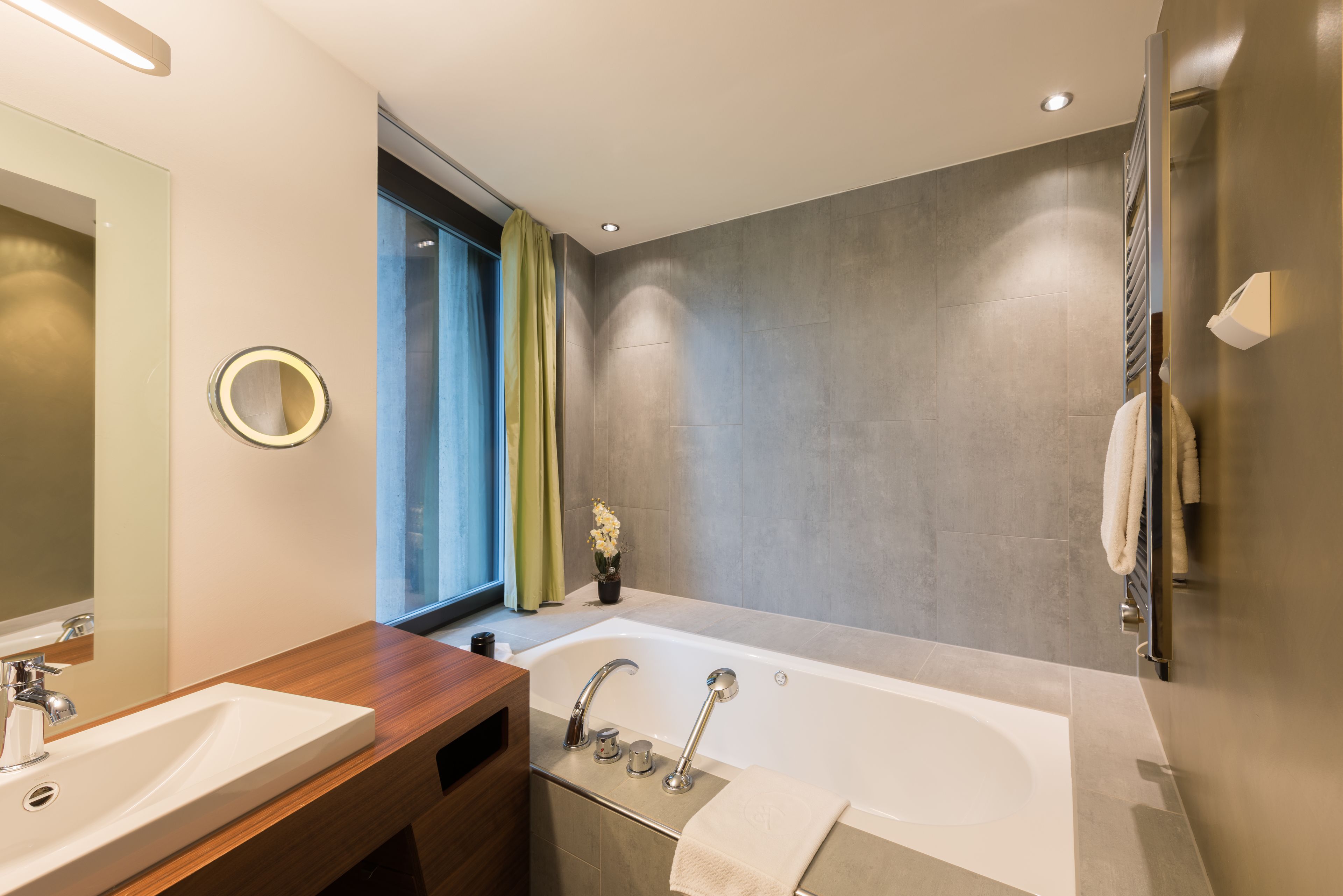 A modern bathroom with a large bathtub, two sinks, a vanity, and a mirror.