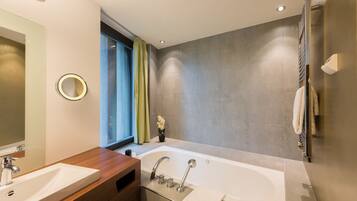 A modern bathroom with a large bathtub, two sinks, a vanity, and a mirror.