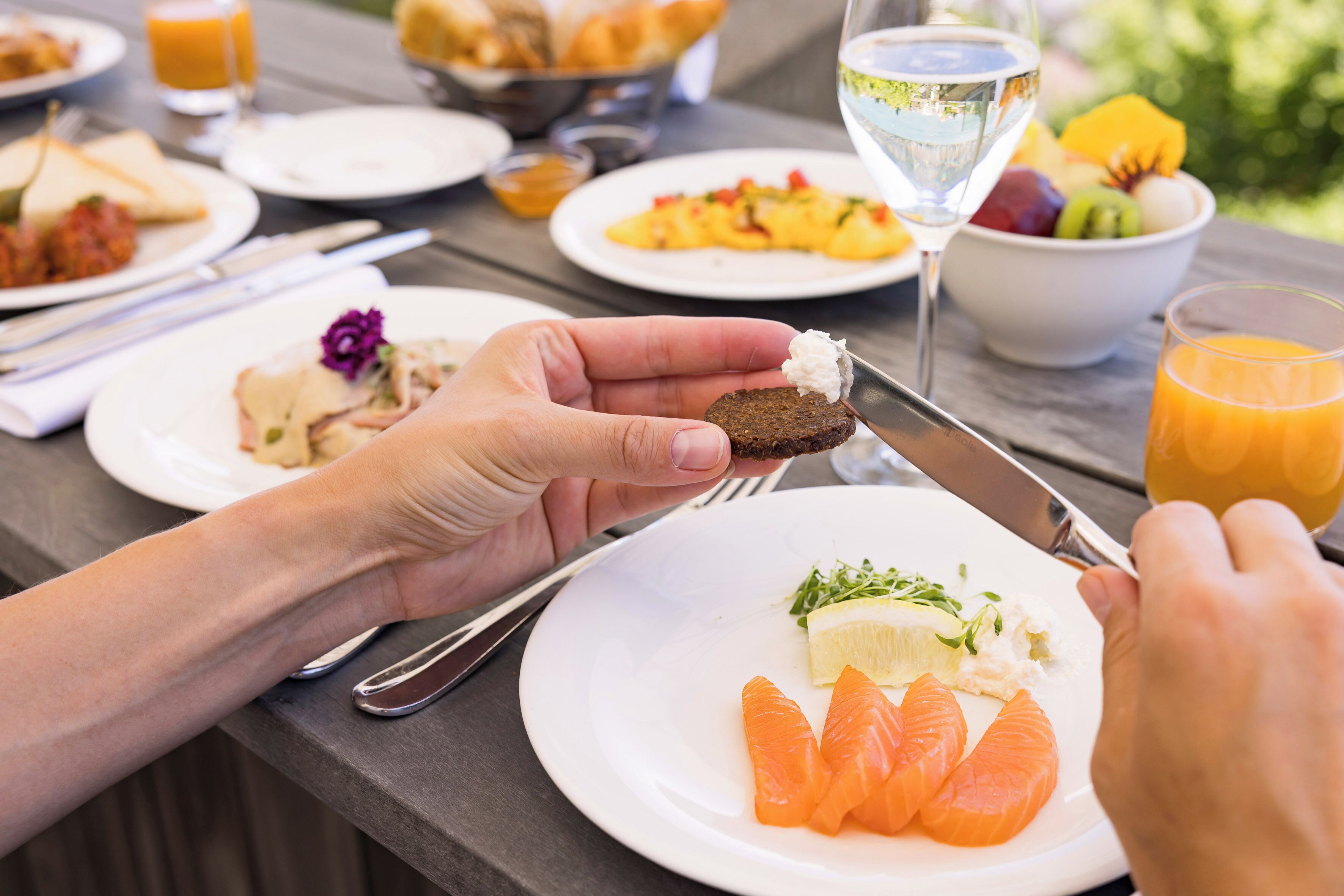 A dining table with plates of food, a glass of white wine, and a glass of orange juice.