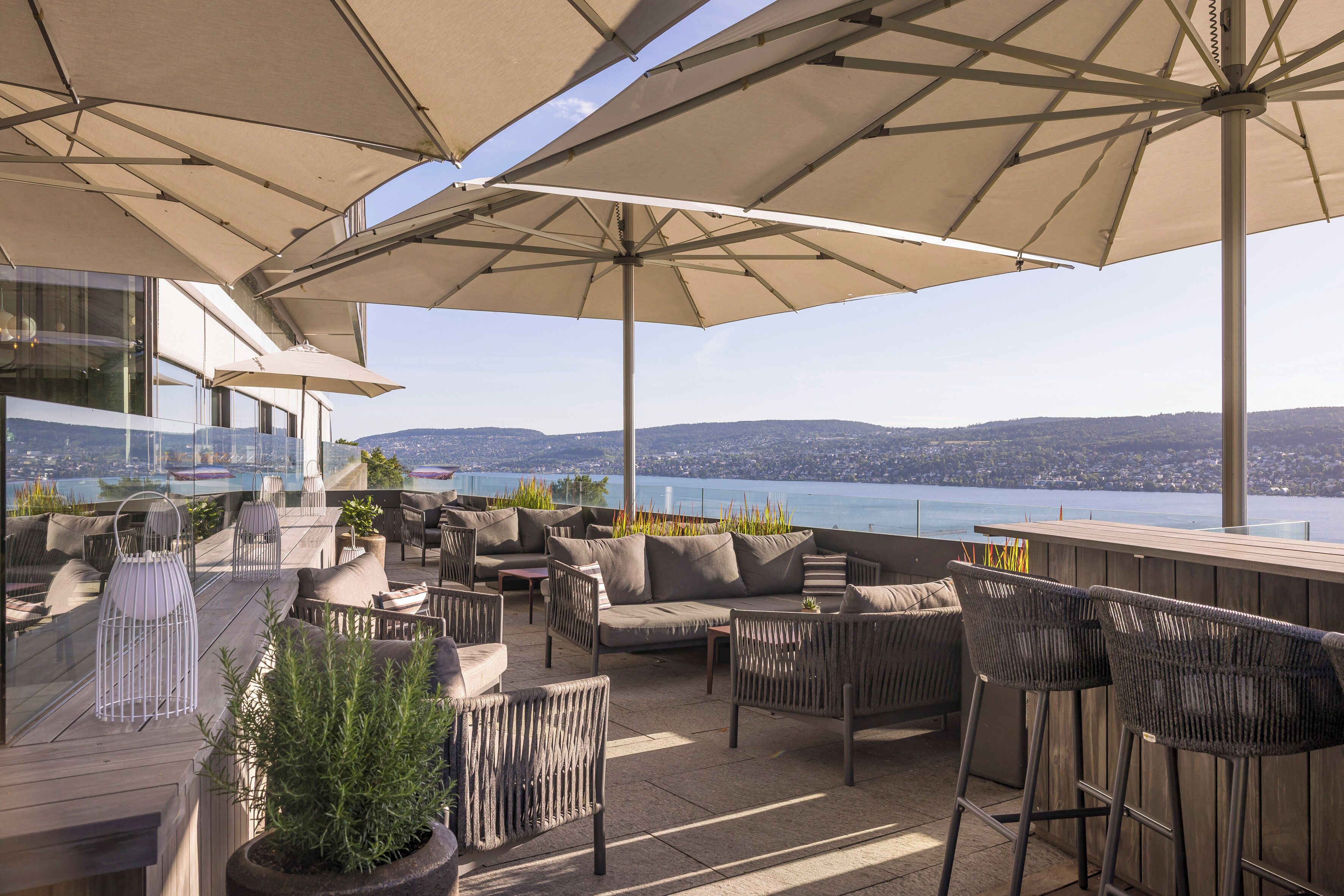 Una terraza en la azotea con asientos al aire libre, sombrillas grandes y vistas a la ciudad y al agua.