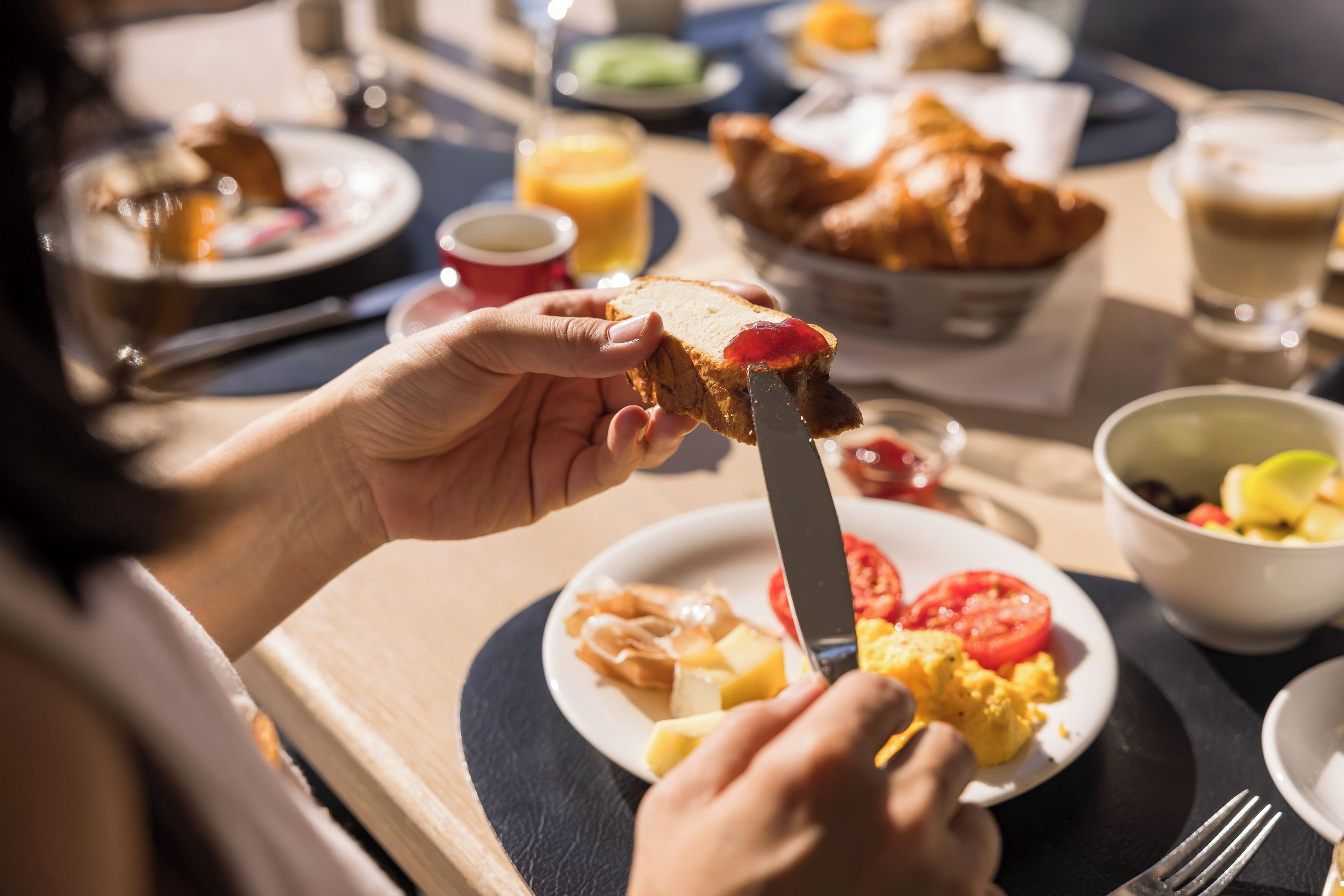 A breakfast setting with toast, scrambled eggs, tomatoes, and croissants.