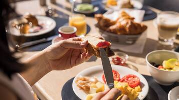 A breakfast setting with toast, scrambled eggs, tomatoes, and croissants.