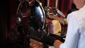 Una persona operando una rebanadora de carne con una rueda grande y un mango.