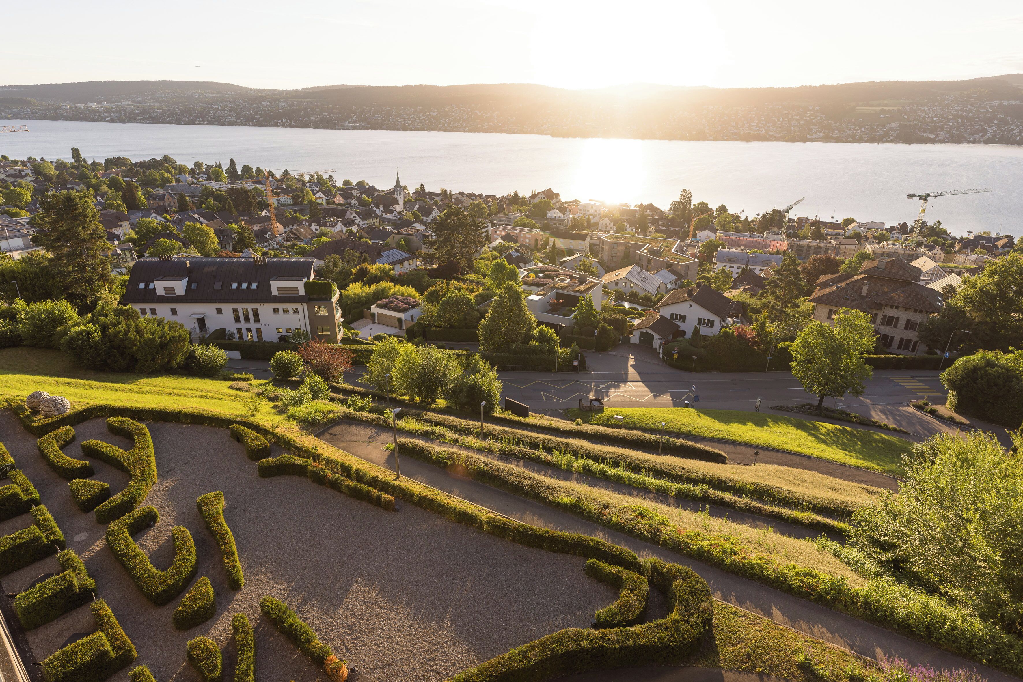 A residential area with a lake, houses, and a well-maintained garden.