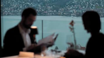 A dining table with a view of a cityscape and a body of water.