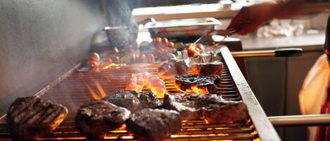 Una parrilla con carne asándose.