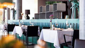 A restaurant with tables set for dining, featuring a modern design with teal accents and white tablecloths.