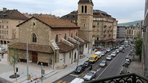A street view with a prominent church featuring a tall tower and a bell tower. - Hotel De Geneve (Geneva)