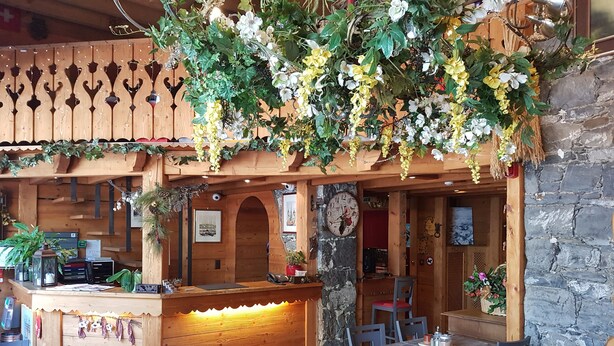 A rustic wooden interior with a reception desk, seating area, and decorative plants. - Hotel De Geneve (Geneva)